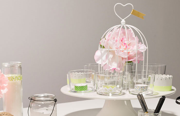 Centre de table composé de fleurs et de bougies installées dans de petits vases en verre Maison Options